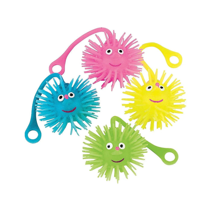 Four colorful puffer ball yoyos with smiling faces in pink, blue, yellow, and green, each with spiky rubber bristles and attached string loops.