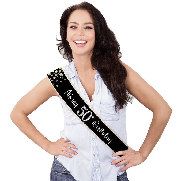 Black satin sash with gold studs and white cursive text reading "It's my 50th Birthday" worn diagonally across a white sleeveless shirt.