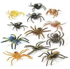Collection of twelve realistic toy spiders in various colors including yellow, black, brown, blue, and tan, arranged on a white background.