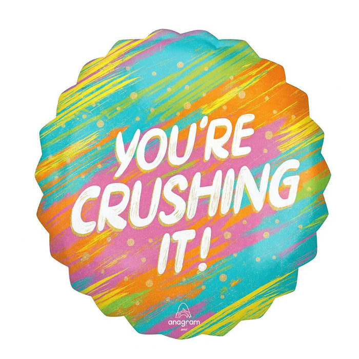 Colorful supershape mylar balloon with rainbow diagonal stripes in turquoise, orange, yellow, pink, and green, featuring white text reading "YOU'RE CRUSHING IT!" and small gold sparkle details throughout.