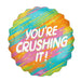 Colorful supershape mylar balloon with rainbow diagonal stripes in turquoise, orange, yellow, pink, and green, featuring white text reading "YOU'RE CRUSHING IT!" and small gold sparkle details throughout.