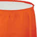 Bright sunkissed orange plastic tableskirt with elasticized top edge and gathered fabric panels displayed against a white background.