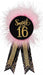 Black circular badge with gold glitter "Sweet 16" text surrounded by pink feather fringe and two black ribbons with gold trim and rhinestone details.