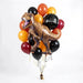 T-Rex dinosaur figurine surrounded by black, orange, yellow, and burgundy latex balloons with an "Aged to Perfection" foil balloon accent and gold ribbons.