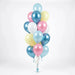 Vertical cluster of metallic and pastel balloons in light blue, dark blue, pink, white, and pale yellow with curled ribbon strings and a blue weight at the base.