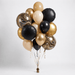 Elegant balloon bouquet featuring black and champagne gold round balloons, decorative marble-patterned spheres, and gold foil accents, tied together with curled ribbons and a weighted base.