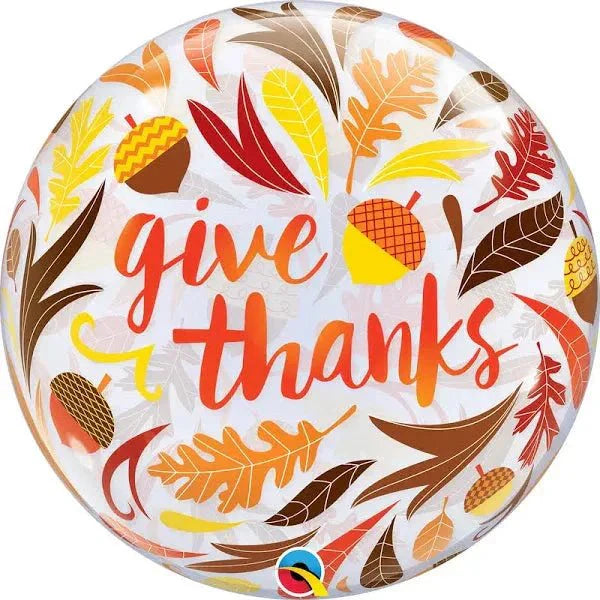 Round clear bubble balloon with red "give thanks" text surrounded by colorful autumn leaves and acorns in yellow, orange, brown, and red.