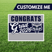 Graduation-themed yard sign with 'Congrats Grad 2026' text and a wolf logo on grass.