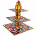 Three-tiered square cupcake stand with international flag patterns on each level and a flame-shaped golden torch centerpiece.