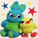 Two colorful plush toy characters, a blue bunny with green belly and a yellow bird with orange beak, sit together surrounded by decorative stars and suns on a striped background.
