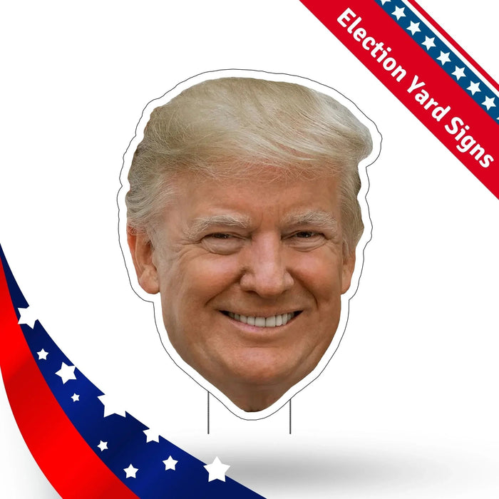 Cardboard cutout head with blonde hair and smiling face on stick supports, with red and blue patriotic striped banner labeled "Election Yard Signs" in upper corners.