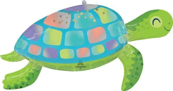 Colorful inflatable turtle balloon with a turquoise shell featuring multicolored squares, bright green flippers and head with closed eye design, and an Anagram brand mark visible on the shell.