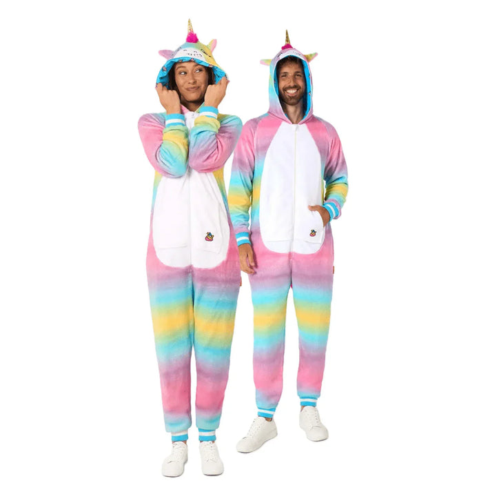 Two people wearing pastel rainbow unicorn onesies with white bellies, colorful striped sleeves and legs, golden horns, and blue hoods with ear details.