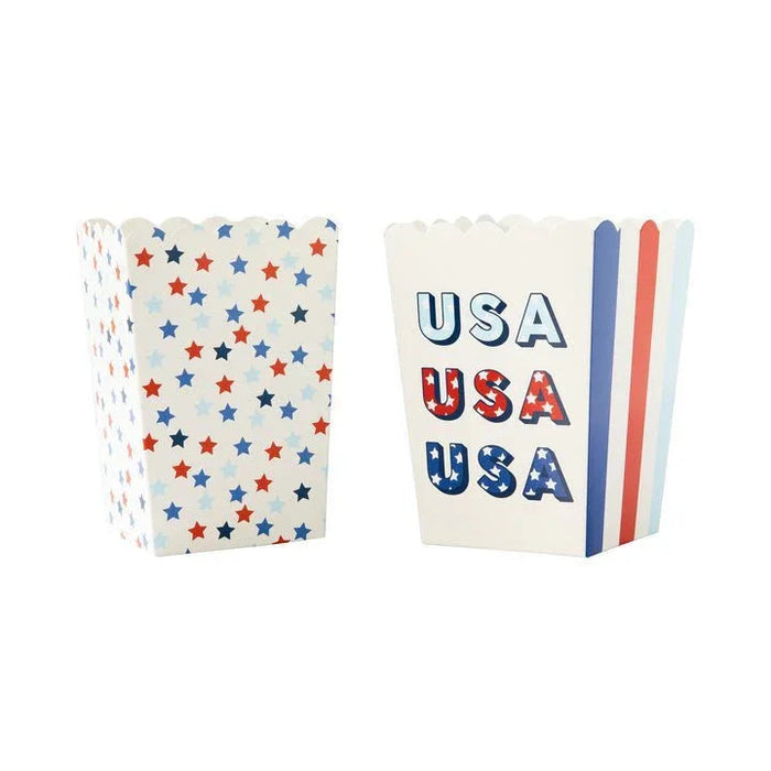 Two patriotic popcorn boxes with scalloped tops: one featuring red, blue, and tan stars allover, the other displaying "USA" text in red and blue with matching striped sides.