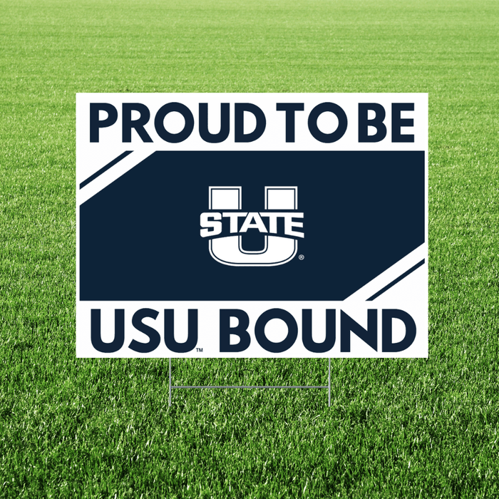 White and navy blue rectangular yard sign with "PROUD TO BE" at top, Utah State University logo in center, and "USU BOUND" at bottom, displayed in grass.