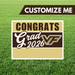 Graduation-themed customizable sign with 'Congrats Grad 2026' text on a grass background