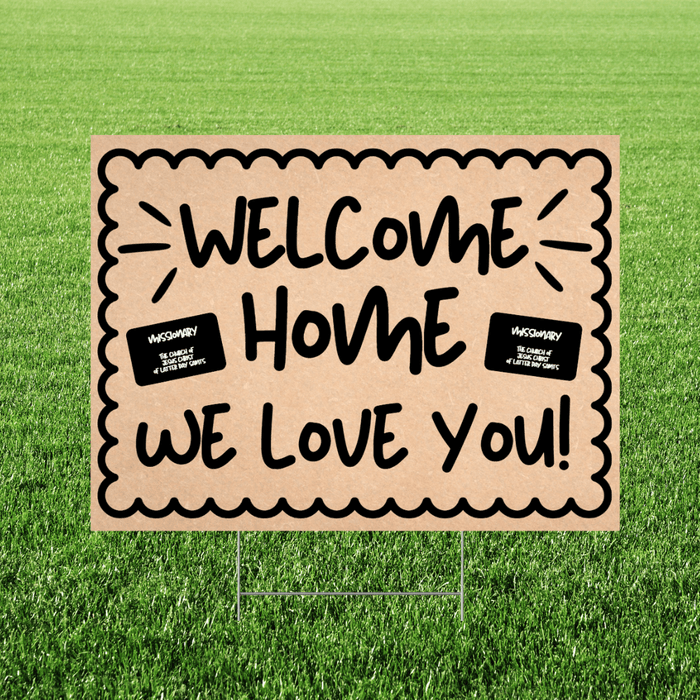 Tan corrugated yard sign with scalloped border edges displaying "WELCOME HOME WE LOVE YOU!" in black hand-painted lettering, with two small missionary name tags on either side, mounted on metal stakes in grass.