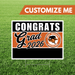 Graduation-themed customizable sign with 'Congrats Grad 2026' text on a grass background