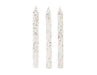 Three tall white taper candles with gold and silver glitter speckles arranged vertically side by side.