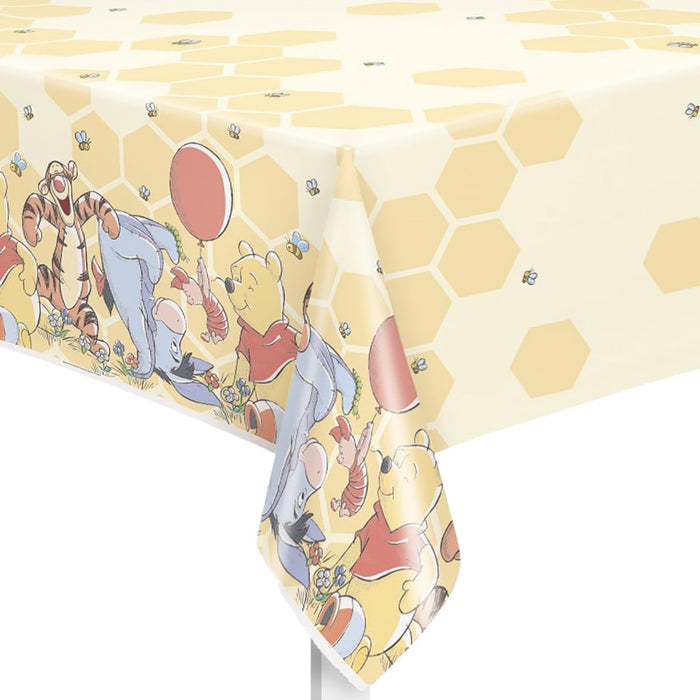 Cream and white plastic tablecloth measuring 54"x84" featuring Winnie the Pooh, Piglet, Tigger, and Eeyore characters with honeycomb patterns and small bees throughout the design.