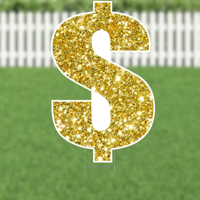 Gold glitter dollar sign yard card with white border and metal stakes, displayed on green grass with white picket fence background.
