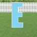 Bright blue letter E yard sign with white outline and metal stakes, displayed on a lawn with white picket fence background.