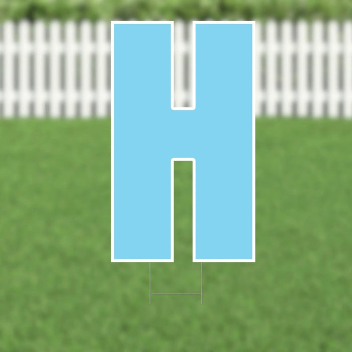 Light blue yard card shaped like the letter H with white border and metal stakes, displayed on grass with white fence in background.
