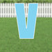 Large light blue letter V yard sign with white border and metal stakes, displayed on a residential lawn with white picket fence in background.