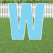 Large light blue letter W yard sign with white outline and metal stake, displayed on grass with white picket fence in background.