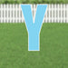 Large light blue letter Y yard sign with white border and metal stakes, displayed on green grass with white picket fence in background.