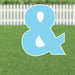 Light blue yard sign shaped like an ampersand symbol with white eye details and metal ground stakes, displayed on green grass with a white picket fence background.