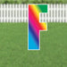 Colorful yard card letter G with a rainbow gradient fill and white outline, displayed on a lawn with white picket fence background.