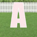 Pink letter A yard sign with white outline and metal stakes, displayed on grass with white picket fence in background.