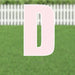 Pink letter D yard sign with white outline and metal stakes, displayed on grass with white picket fence background.