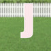 Pink letter J yard sign with white border and metal stakes, displayed on green grass with white picket fence backdrop.