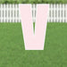 Large pink letter V yard sign with white border and metal stakes, displayed on green grass with white picket fence in background.