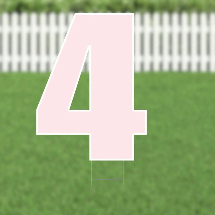 Large pink number 4 yard sign with white outline and metal stakes, displayed on green lawn with white picket fence in background.