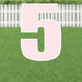 Pink yard card number 5 with white outline displayed on grass with white picket fence in background.
