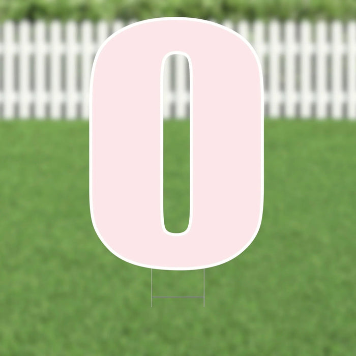 Large pink yard sign shaped like the number zero with white border and metal stakes, displayed on green grass with white picket fence background.