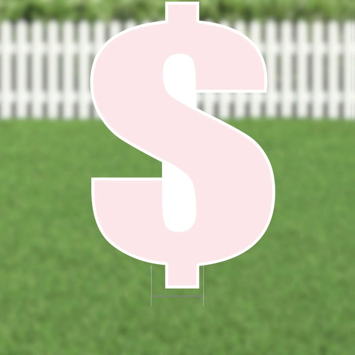 Large pink dollar sign yard decoration with white outline and metal ground stakes, displayed on green grass with white picket fence background.