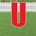 Red capital letter U yard sign with white border and metal stakes, displayed on green grass with white picket fence background.