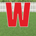 Red letter W yard sign with white border and metal stakes, displayed on grass with white picket fence in background.
