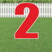 Large red number 2 yard sign with white outline and metal stakes, displayed on green grass with white picket fence background.