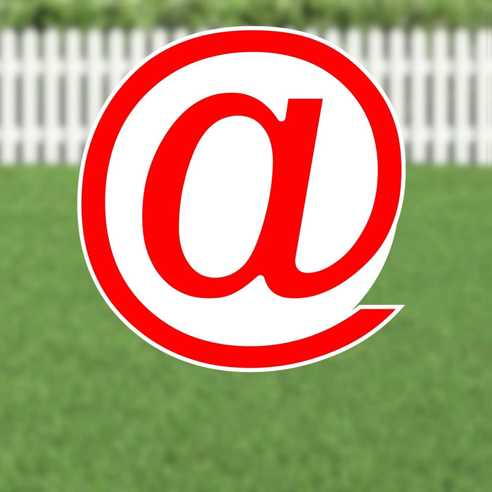 Red circular yard sign with a white @ symbol displayed against a green lawn and white picket fence background.
